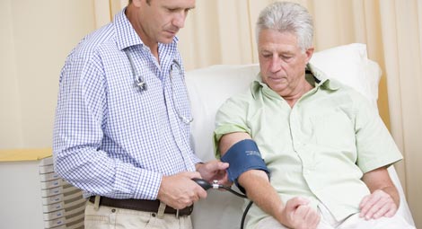 Doctor taking blood pressure of an older man